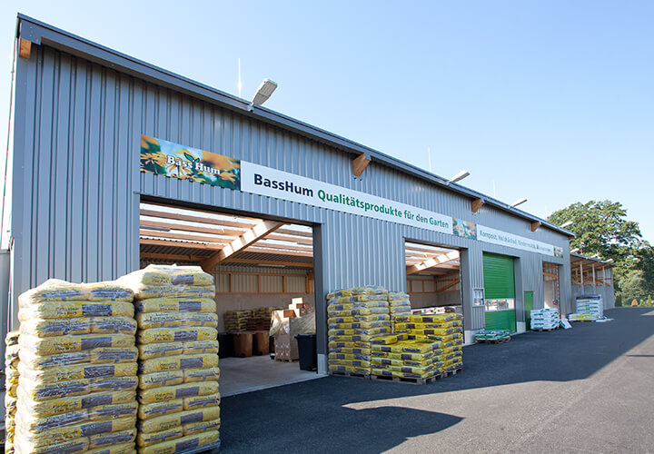 Eine Lagerhalle von BassHum mit offenen Toren, davor stehen Paletten mit Blumenerde in Säcken